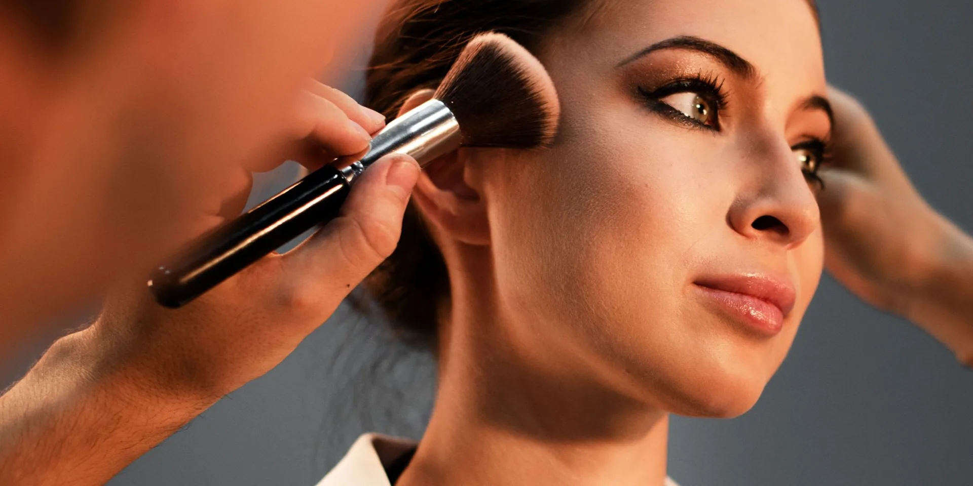 Makeup artist sculpting a client's cheekbones with a contour brush